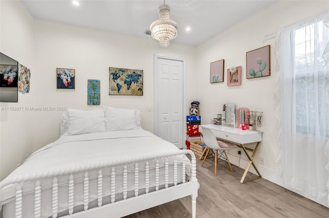 bedroom featuring baseboards, recessed lighting, a closet, a notable chandelier, and light wood-type flooring