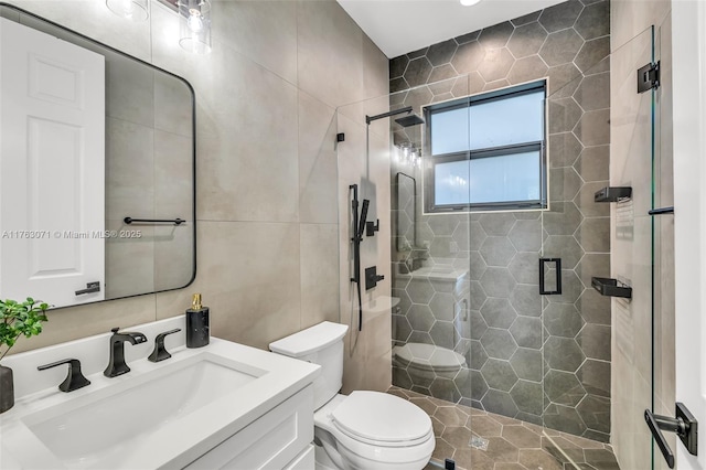 full bath featuring vanity, tile walls, toilet, and a shower stall