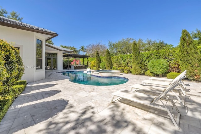 view of pool with a pool with connected hot tub, a patio area, and french doors