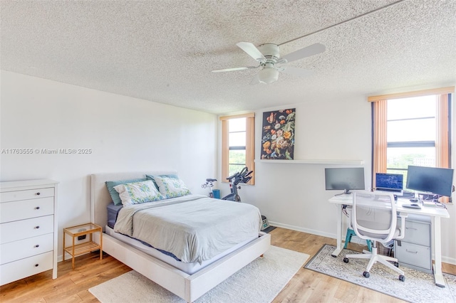 bedroom featuring baseboards, a textured ceiling, a ceiling fan, and wood finished floors