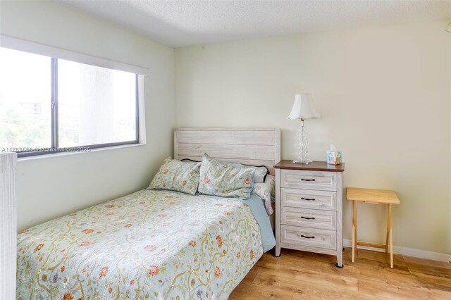 bedroom with baseboards, a textured ceiling, and wood finished floors