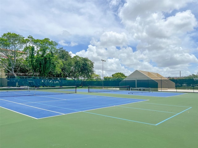 view of tennis court with community basketball court and fence