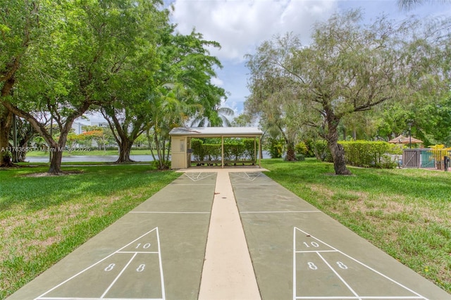 view of home's community with a lawn, shuffleboard, and fence