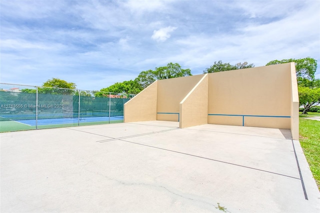 view of property's community featuring a tennis court and fence