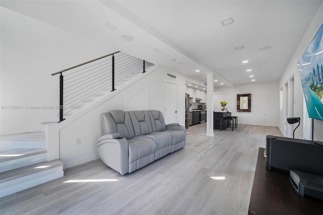 living room featuring stairs, recessed lighting, baseboards, and light wood-type flooring