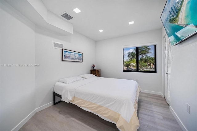 bedroom featuring visible vents, baseboards, a closet, and wood finished floors