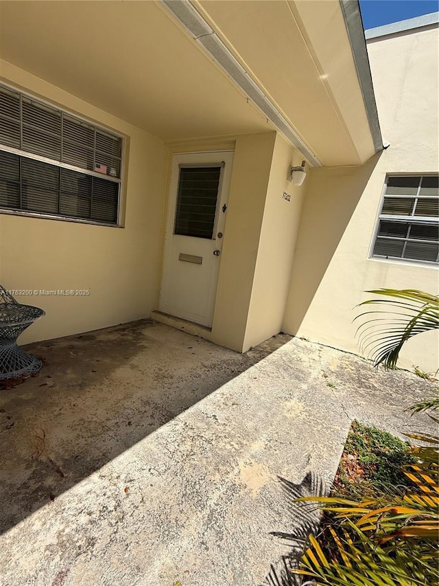 property entrance featuring stucco siding and a patio