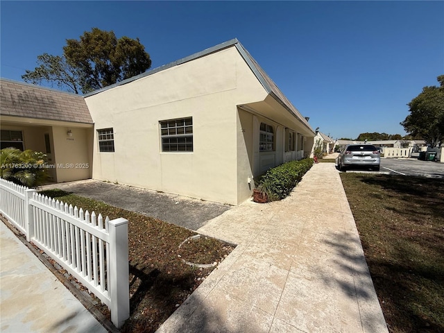 view of side of property featuring stucco siding and fence