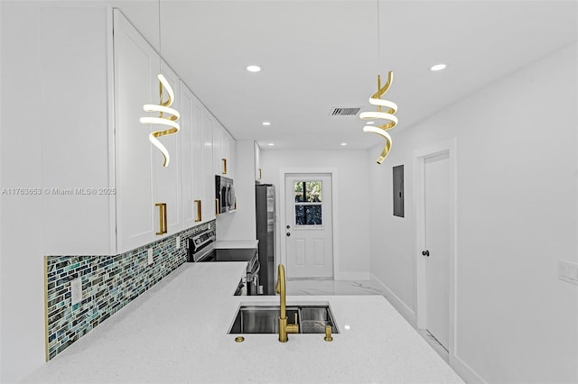 kitchen with backsplash, light stone counters, appliances with stainless steel finishes, white cabinetry, and a sink