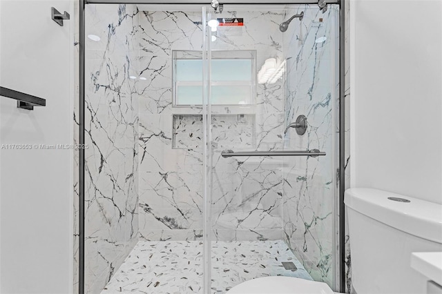 bathroom with toilet and a marble finish shower