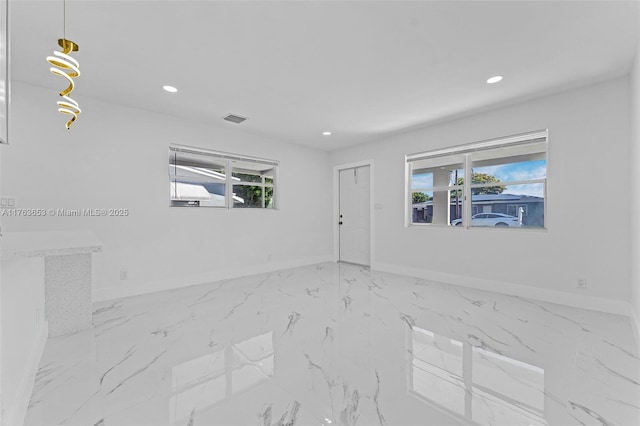 empty room with a wealth of natural light, recessed lighting, marble finish floor, and baseboards