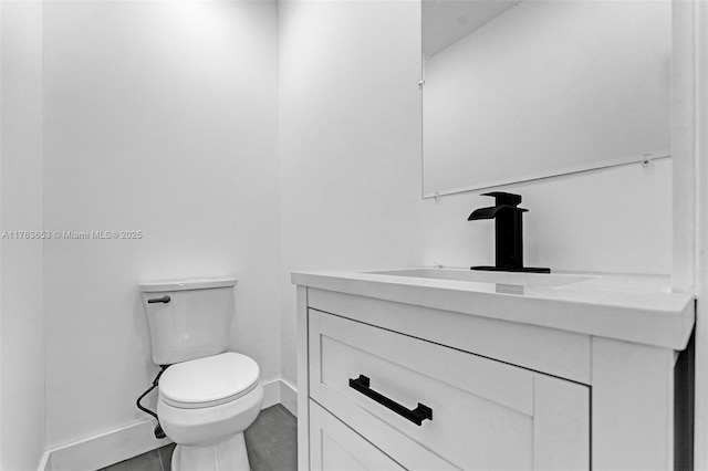 bathroom with toilet, vanity, and baseboards