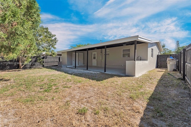 back of property with stucco siding, a patio, a lawn, and a fenced backyard