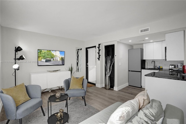 living room featuring recessed lighting, visible vents, light wood-style flooring, and baseboards