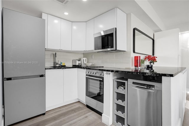 kitchen featuring decorative backsplash, light wood-style floors, appliances with stainless steel finishes, and white cabinets