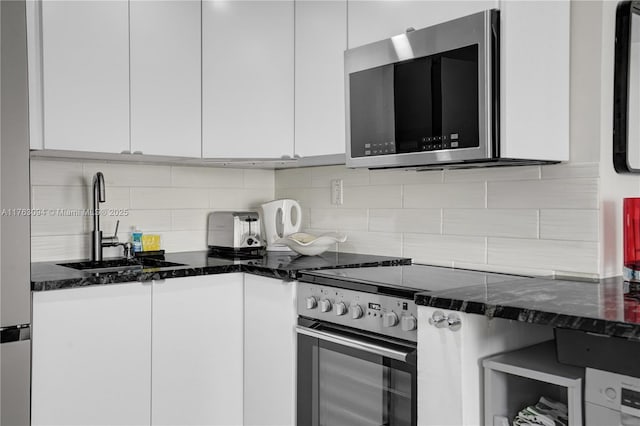 kitchen featuring dark stone counters, a sink, electric range oven, white cabinetry, and stainless steel microwave