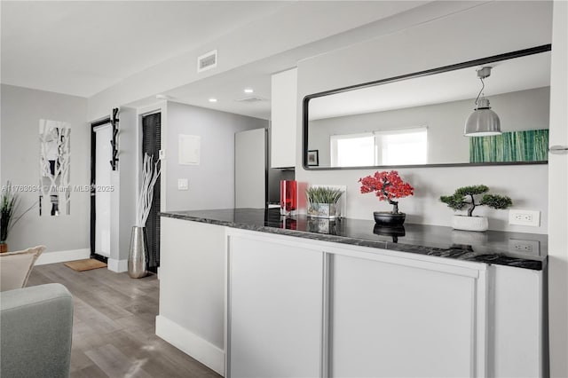 kitchen with wood finished floors, visible vents, baseboards, dark stone counters, and recessed lighting