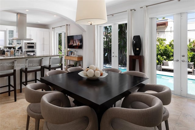 dining space with french doors, arched walkways, and a healthy amount of sunlight