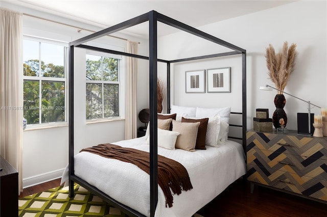 bedroom with baseboards, multiple windows, and wood finished floors