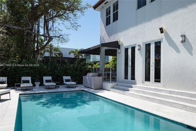 outdoor pool featuring french doors and a patio area