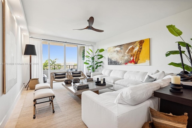 living area with baseboards and ceiling fan