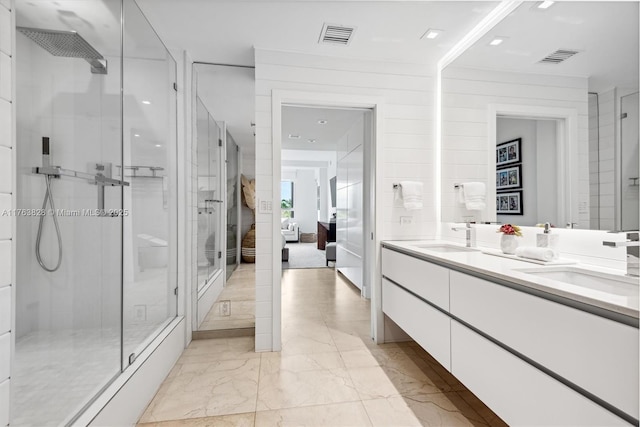 bathroom featuring a sink, marble finish floor, a shower stall, and double vanity