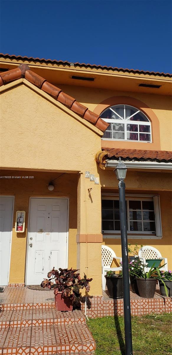 doorway to property featuring a tile roof and stucco siding