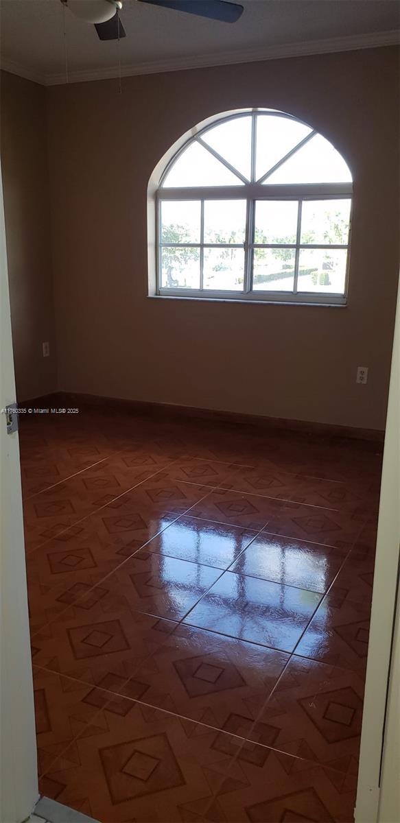 spare room featuring crown molding, plenty of natural light, baseboards, and ceiling fan