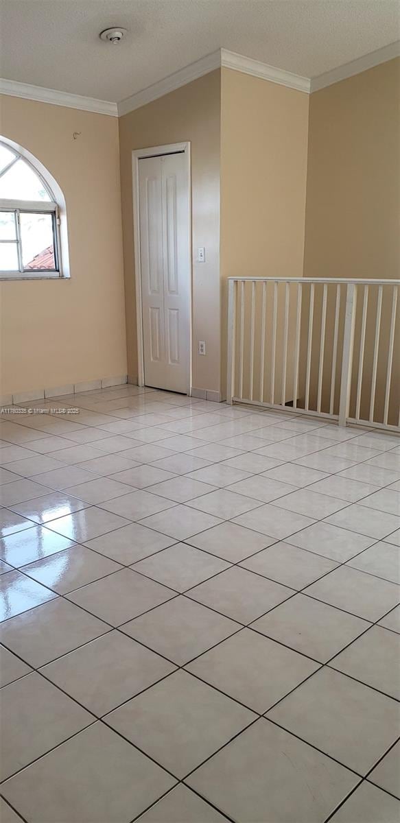 spare room featuring light tile patterned floors, a textured ceiling, and ornamental molding