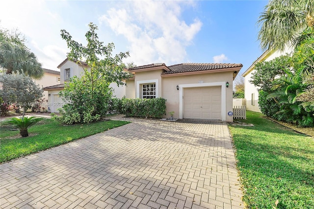 mediterranean / spanish-style home with a tile roof, decorative driveway, a garage, and stucco siding