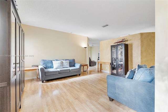 living room featuring visible vents, baseboards, french doors, a textured ceiling, and light wood-type flooring