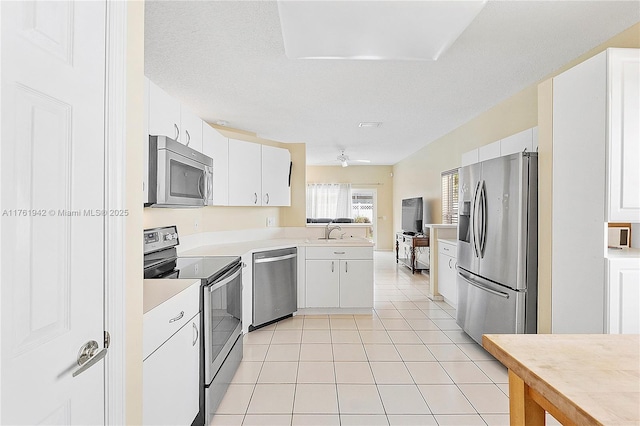 kitchen with a sink, white cabinetry, appliances with stainless steel finishes, light countertops, and light tile patterned floors