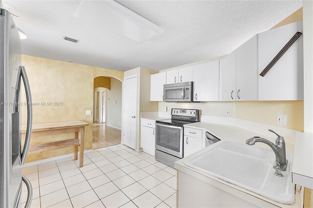 6244 NW 38th Dr, Coral Springs, FL 33067 - kitchen featuring appliances with stainless steel finishes, a sink, arched walkways, light countertops, and white cabinets