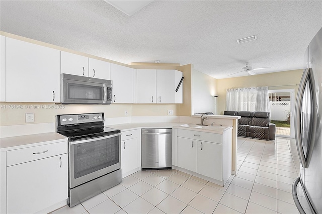 kitchen with a peninsula, light countertops, open floor plan, and stainless steel appliances