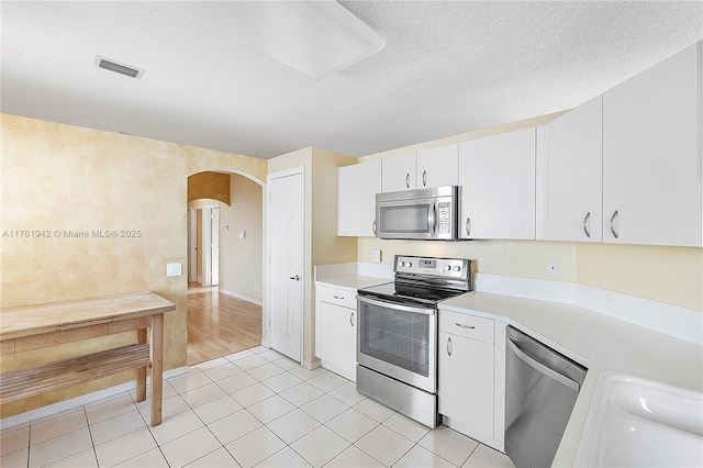 kitchen with stainless steel appliances, arched walkways, visible vents, and light countertops