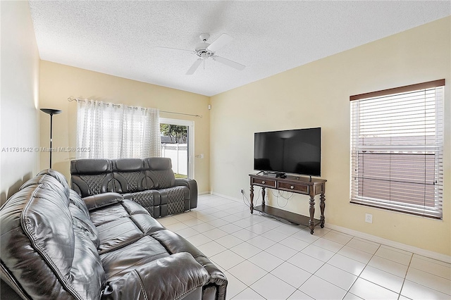 living area featuring light tile patterned flooring, baseboards, a textured ceiling, and a ceiling fan