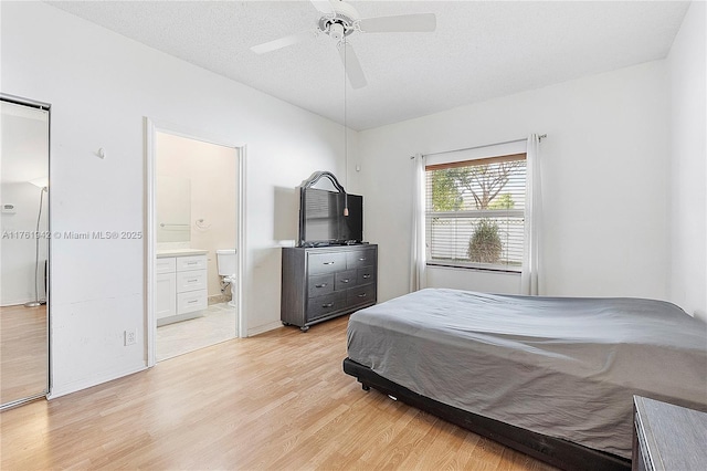 bedroom with ensuite bath, a textured ceiling, light wood-type flooring, and ceiling fan