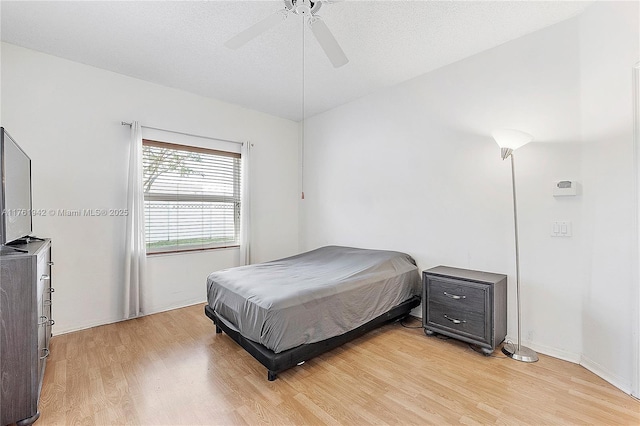 bedroom featuring a textured ceiling, light wood-style flooring, and a ceiling fan