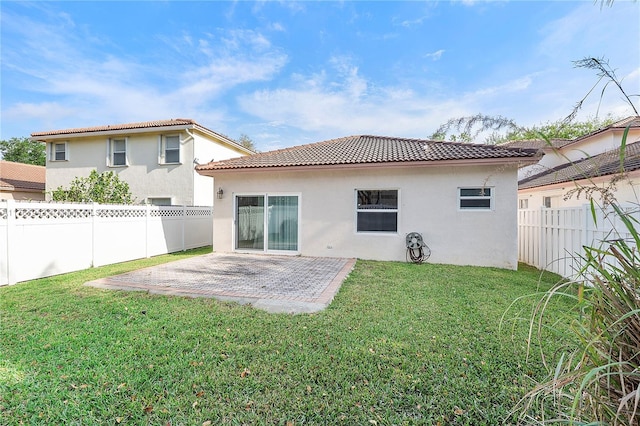 rear view of house featuring a patio, a yard, a fenced backyard, stucco siding, and a tile roof