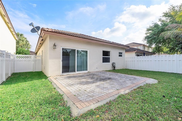 back of house featuring a yard, a fenced backyard, stucco siding, a tiled roof, and a patio area