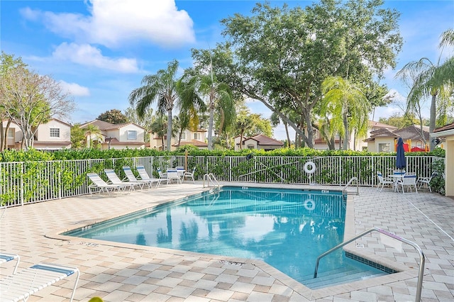 community pool featuring a patio area, fence, and a residential view