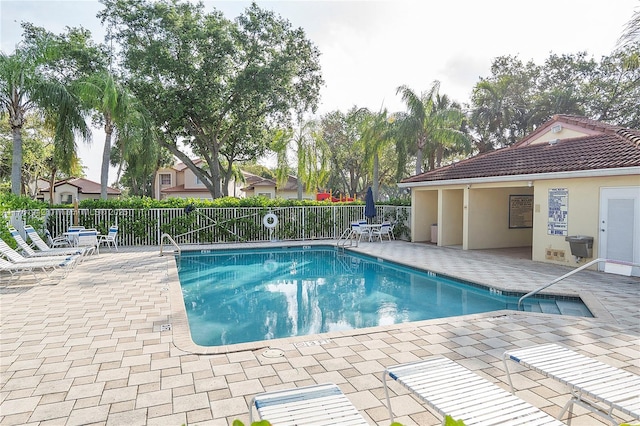 pool with a patio area and fence