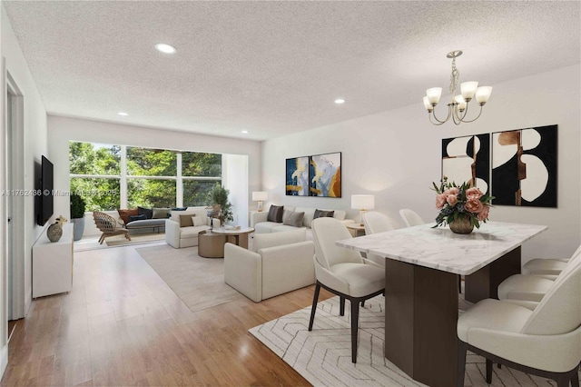 dining room featuring a notable chandelier, recessed lighting, a textured ceiling, and light wood-type flooring