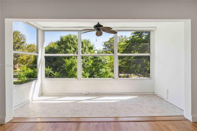 unfurnished room featuring a wealth of natural light, wood finished floors, and ceiling fan