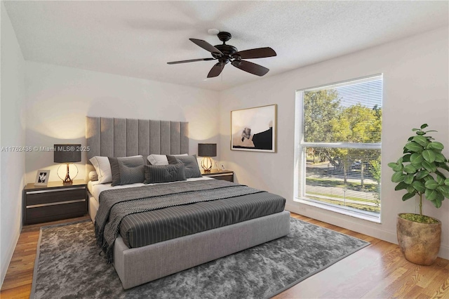 bedroom with a textured ceiling, wood finished floors, and a ceiling fan