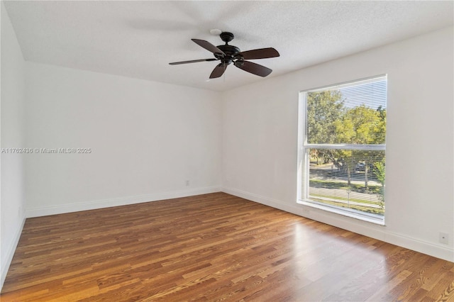 empty room with wood finished floors, a healthy amount of sunlight, and baseboards