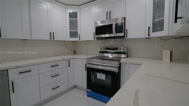 kitchen featuring glass insert cabinets, backsplash, appliances with stainless steel finishes, and white cabinetry