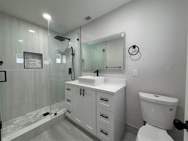 full bathroom with visible vents, toilet, a stall shower, and vanity