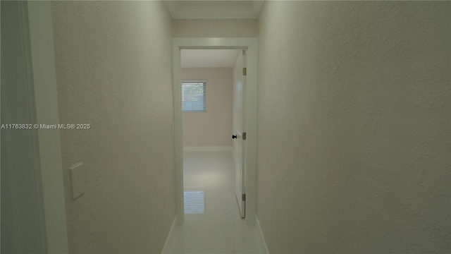 hall with a textured wall and ornamental molding