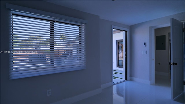 hallway with a wealth of natural light, tile patterned flooring, electric panel, and baseboards